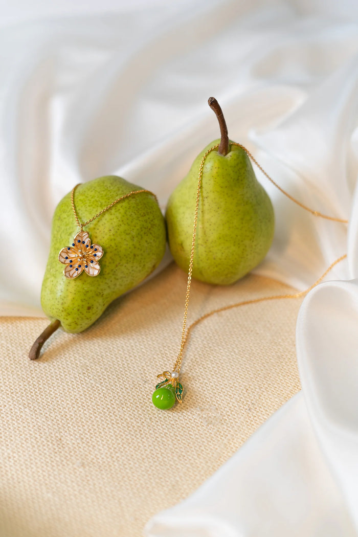 Garden Pear Necklace_Necklace with an enamelled pear pendant with faux pearl and gold chain on a white background